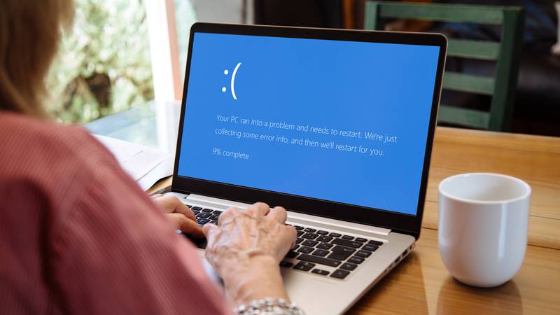 Woman with laptop showing Blue screen of death or BSOD on the monitor screen. Faulty Microsoft operating system Windows 10.